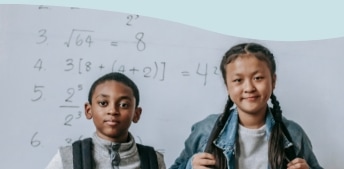 Two students with backpacks stand in front of a whiteboard with math equations written on it.