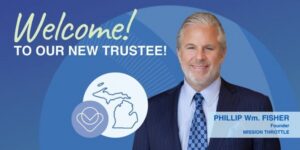 A smiling man in a suit is welcomed as a new trustee. Text reads “Welcome! To our new trustee! PHILLIP Wm. FISHER, Founder, MISSION THROTTLE.” Michigan state outlines and a heart icon are shown.